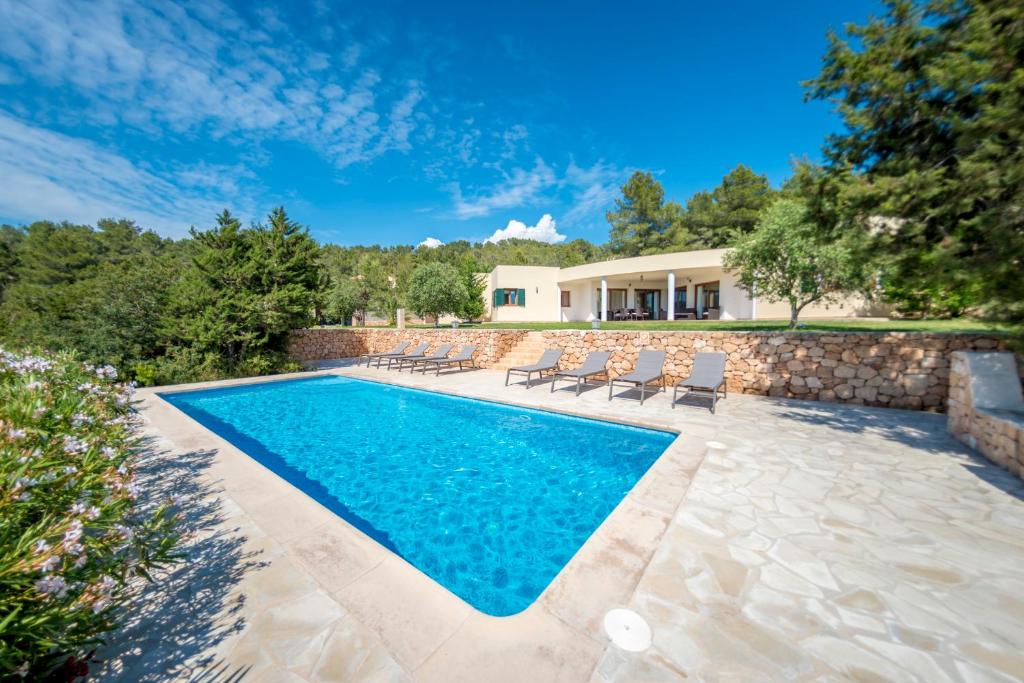a swimming pool with chairs and a house at Sa Lluna in Sant Josep