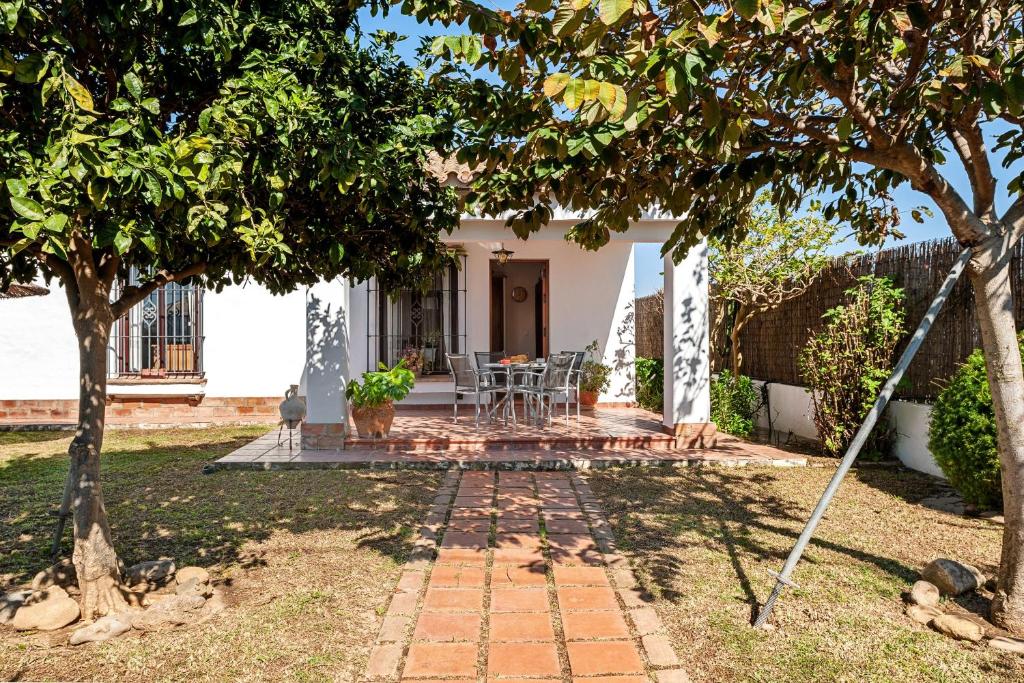 ein Haus mit einer Terrasse und Bäumen im Hof in der Unterkunft Cortijo Villa La Dehesa in Conil de la Frontera