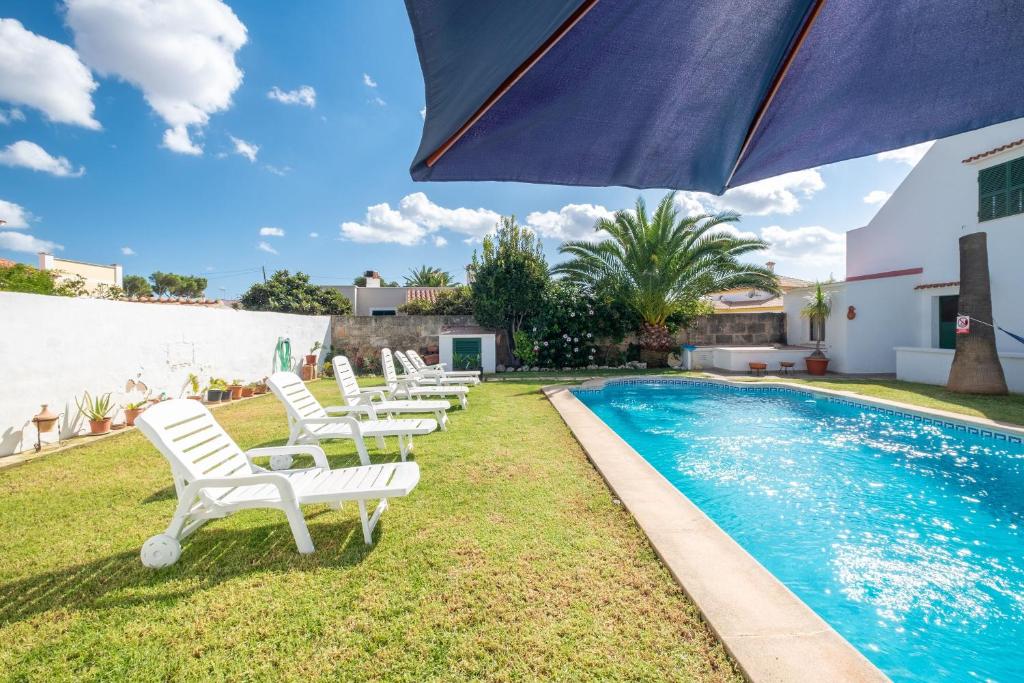 - un groupe de chaises blanches installées à côté de la piscine dans l'établissement Villa en Son Gall Ciutadella, à Ciutadella