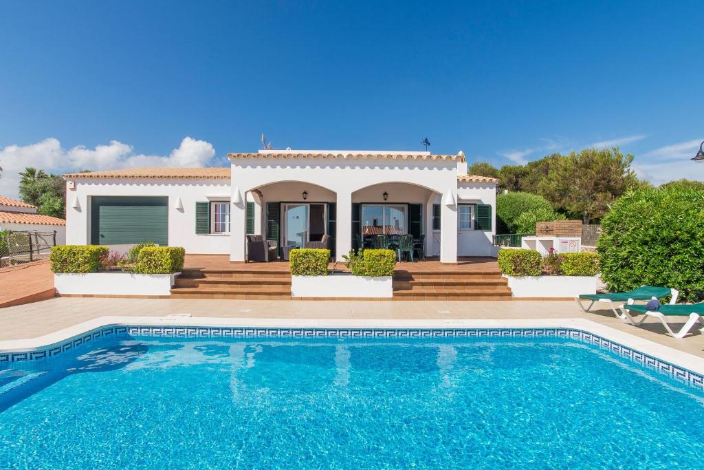 a villa with a swimming pool in front of a house at Villa Bini Tuduri in Binibeca