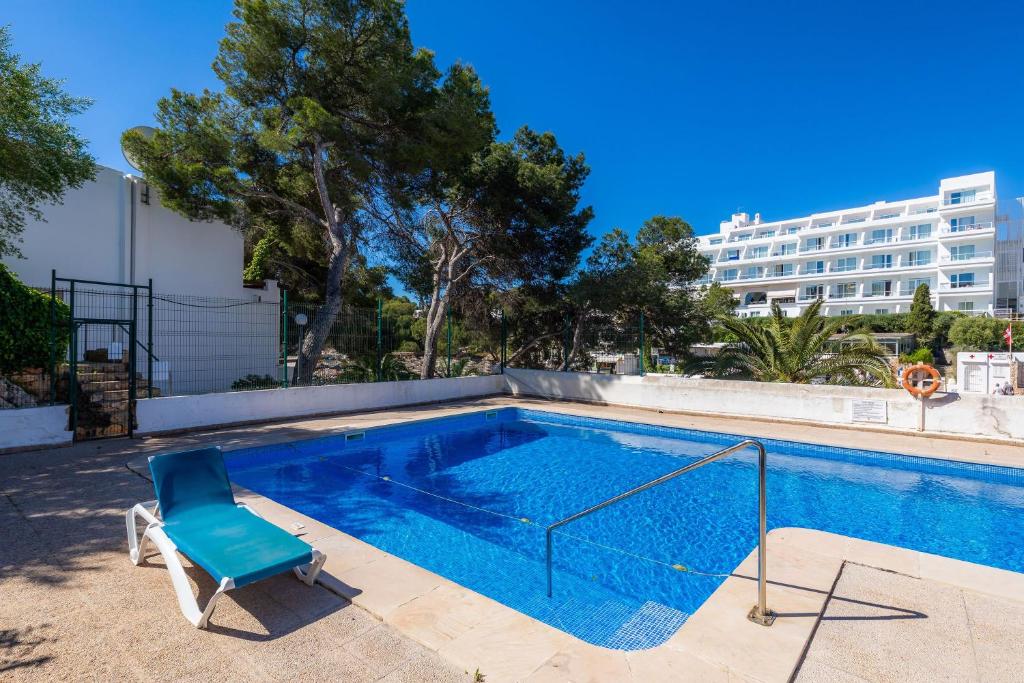 uma piscina com uma cadeira azul ao lado de um edifício em Beach Apartment 11 em Cala d´Or