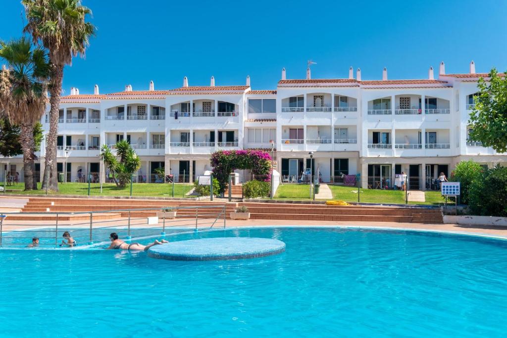 une piscine en face d'un grand bâtiment dans l'établissement Apartamento Cala'n Blanes, à Cala en Blanes