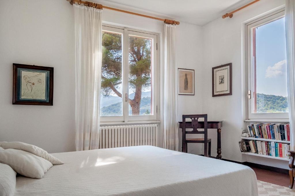 una camera da letto con un grande letto bianco e due finestre di Il Grifo - Cozy house, wonderful view a Portoferraio