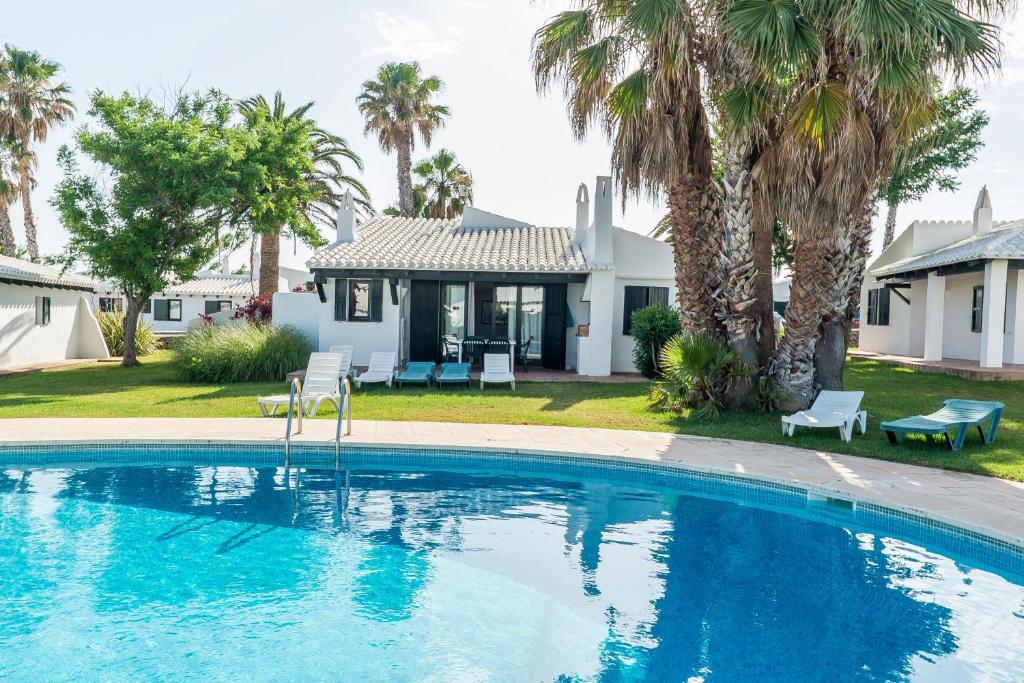 a swimming pool in front of a house with palm trees at Casa 5 Q en Complejo Binisafua in Binisafua