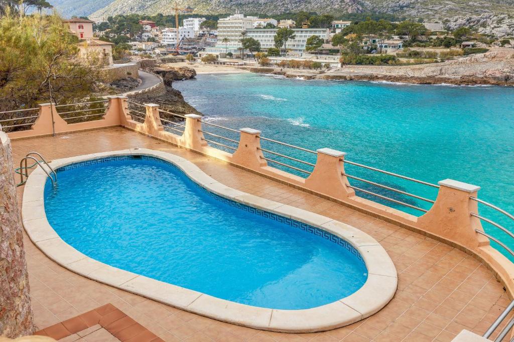 a large swimming pool next to a body of water at Apartamento Mirador 6i in Cala de Sant Vicent