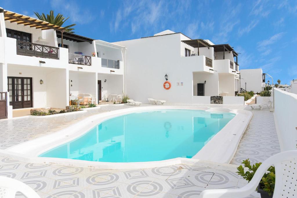 a villa with a swimming pool in front of a building at Apartamento Los Morales in Puerto del Carmen