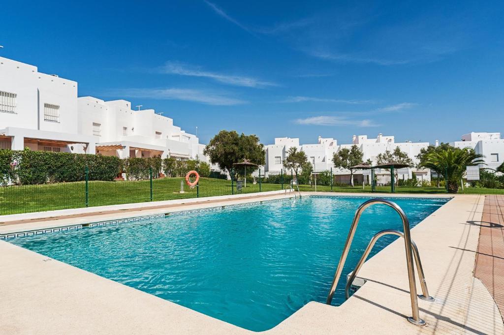 コニル・デ・ラ・フロンテーラにあるDúplex 2 habitaciones, piscina Solo mayores de 30の青い水のスイミングプールと建物を背景に