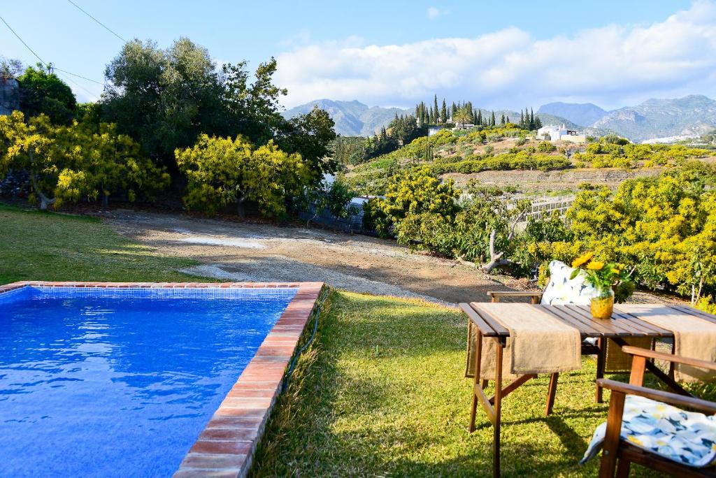 un patio trasero con una mesa y una piscina en Casa entre Nerja y Frigiliana, en Frigiliana