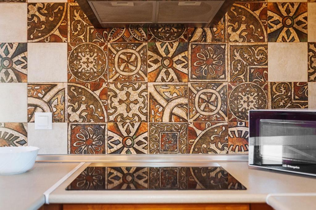 a kitchen with a tile wall with a laptop on a counter at Las tres hermanas in Conil de la Frontera