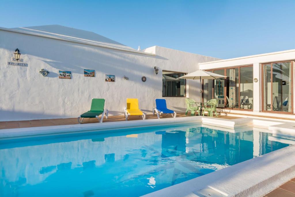 a swimming pool with colorful chairs next to a house at Casa Margarita in Las Breñas