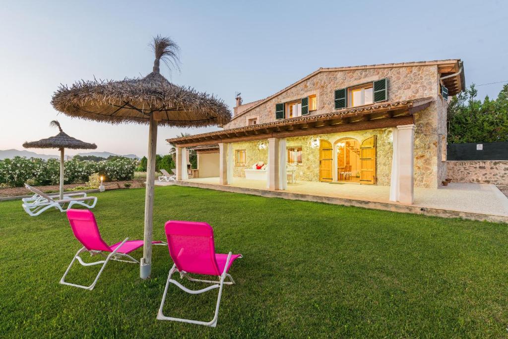 einen Hof mit zwei Stühlen, einem Regenschirm und einem Haus in der Unterkunft Can Ferrer in Alcúdia