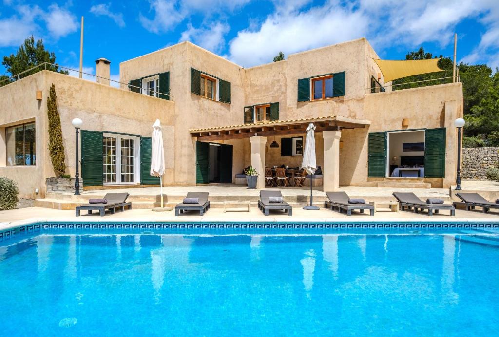 uma casa com piscina em frente a uma casa em Can Moustique em Sant Josep de sa Talaia