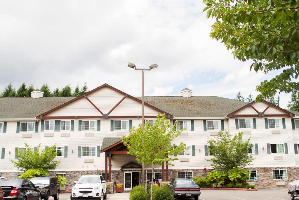 a large white building with cars parked in a parking lot at FairBridge Inn & Suites DuPont in DuPont