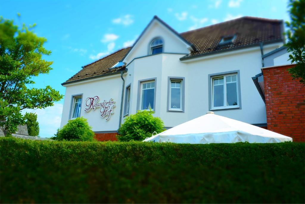 ein weißes Haus mit einem weißen Regenschirm davor in der Unterkunft Klausdorfer Hof in Schwentinental