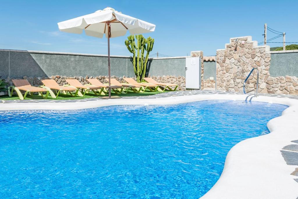 a swimming pool with an umbrella and chairs and a swimming pool at Bungalows La Aceitera - Apartamento 2 in Zahora