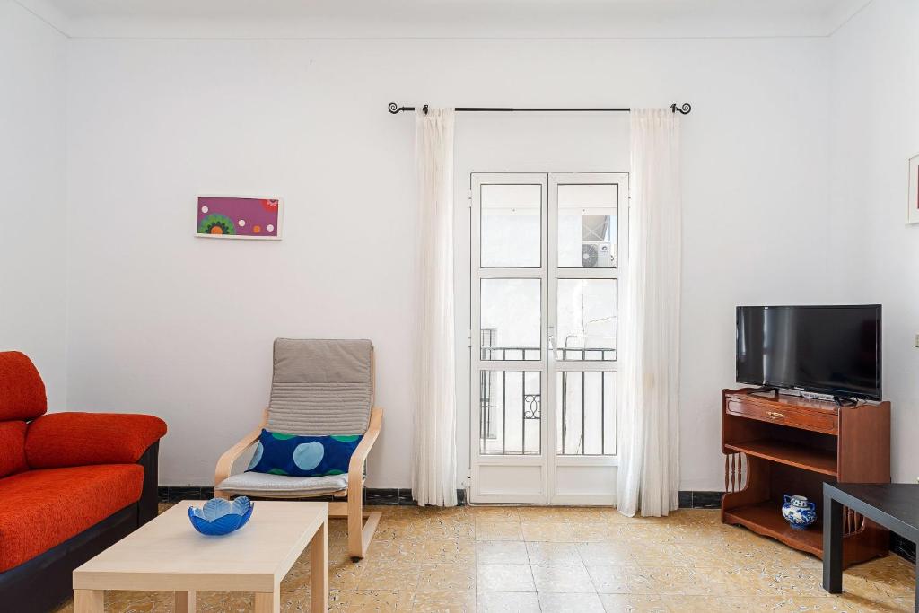 a living room with a red couch and a tv at Apartamento Nicolas Only Families in Conil de la Frontera