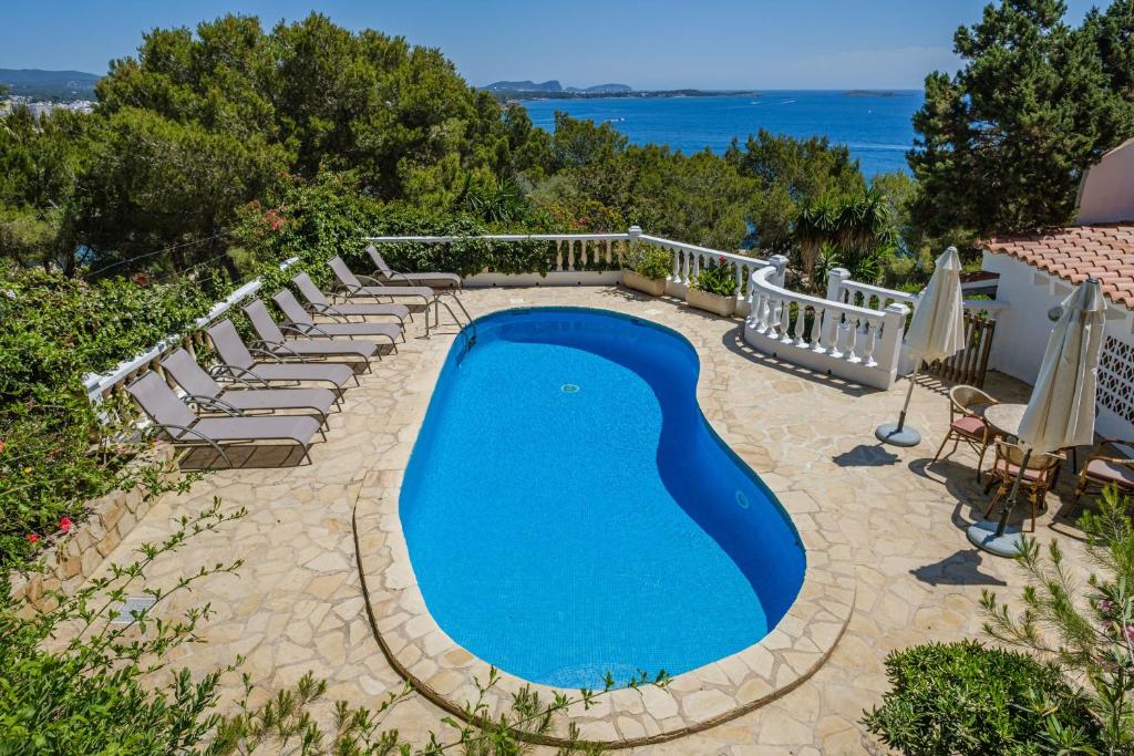 een zwembad met ligstoelen eromheen en de oceaan bij Shangri-la in Santa Eularia des Riu
