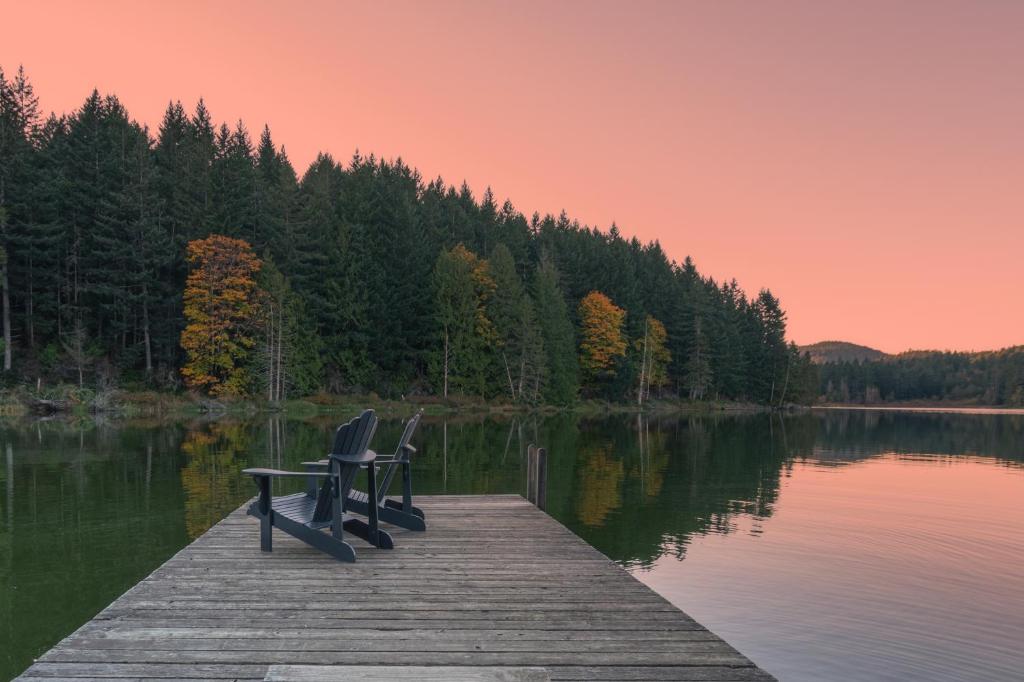 2 chaises assises sur un quai sur un lac dans l'établissement Cusheon Lake Resort, à Ganges