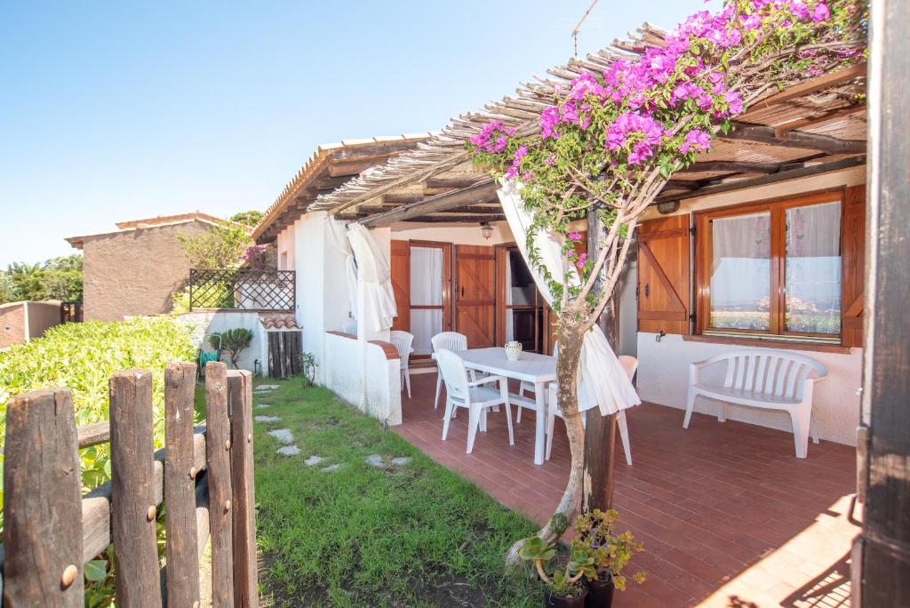 un patio con mesa, sillas y una valla en Casa Baja Sardinia, en Baja Sardinia