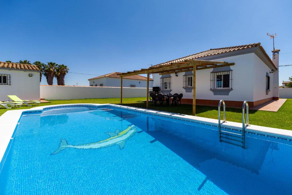 a swimming pool in front of a house at Chalet Isla del Sotillo in Chiclana de la Frontera