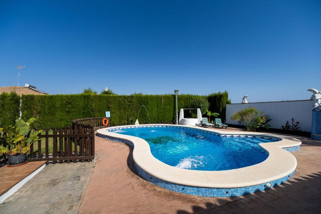 a swimming pool in a backyard with a fence at Cortijo Entrepinares in Conil de la Frontera