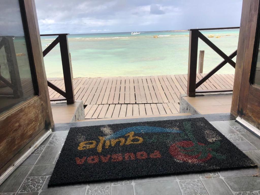a welcome mat in front of a door with the ocean at Pousada Tranquila in Morro de São Paulo