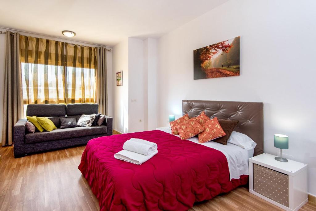 1 dormitorio con 1 cama grande de color rojo y 1 sofá en Loft, en Málaga