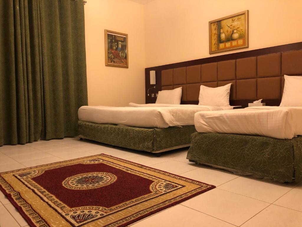 a bedroom with two beds and a rug on the floor at New Royal Mark Hotel Apartments in Dubai