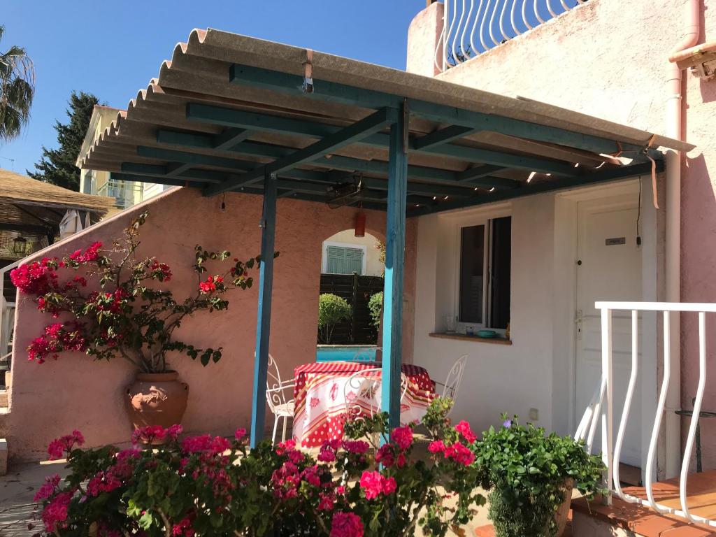 uma pérgola na parte de trás de uma casa com flores em Rez de Jardin Villa Cagnes Sur Mer. em Cagnes-sur-Mer