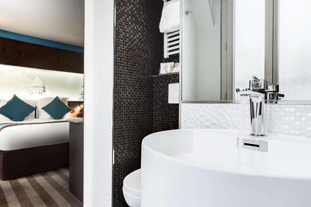 a white bath tub sitting next to a white sink at Best Western Nouvel Orléans Montparnasse in Paris