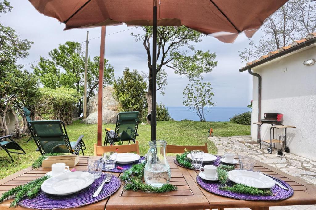 einem Holztisch mit Teller mit Lebensmitteln und einem Regenschirm in der Unterkunft Casa La Capraia in Zanca