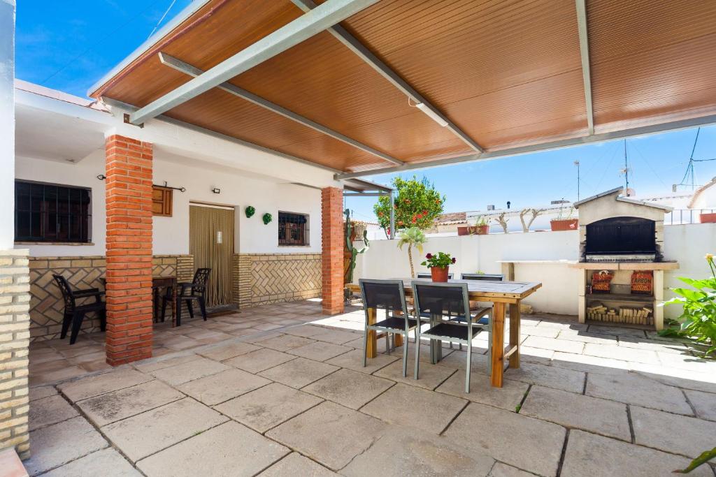 un patio al aire libre con pérgola de madera, mesa y sillas en Casa Basallote, en El Palmar