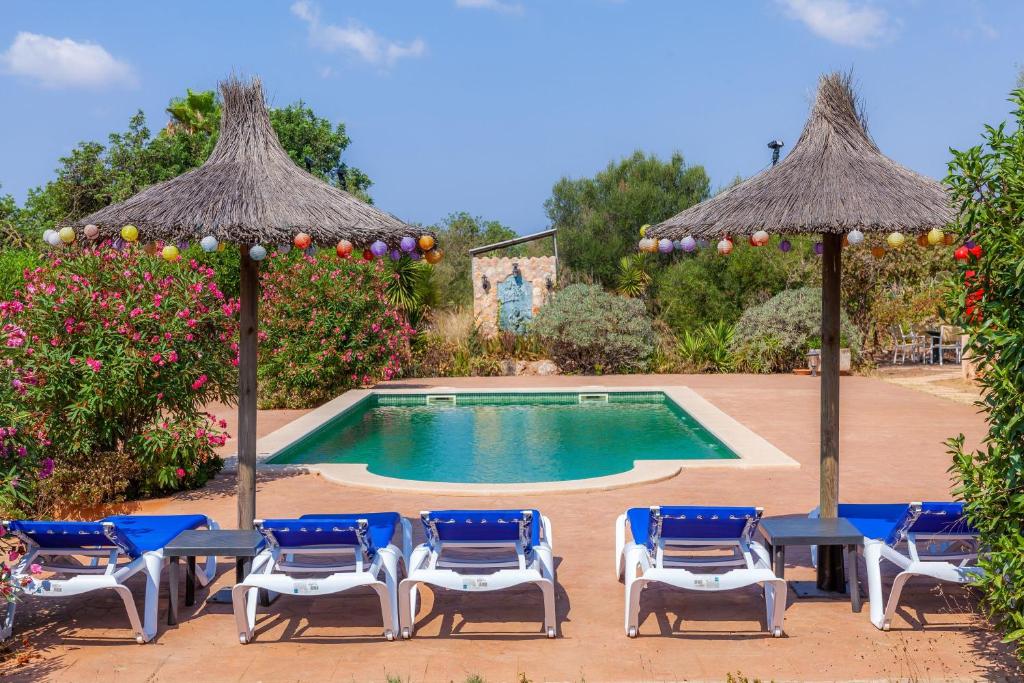 a swimming pool with chairs and umbrellas at Geminis in Llucmajor