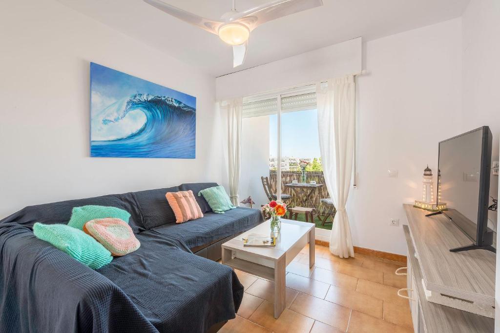 un soggiorno con divano blu e TV di Apartamento "soñac sol" a Los Caños de Meca