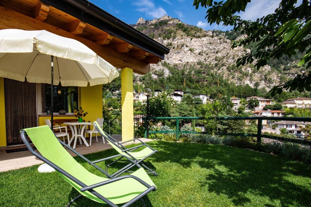 patio z 2 krzesłami ogrodowymi i parasolem w obiekcie Appartamento Giada w Tremosine Sul Garda