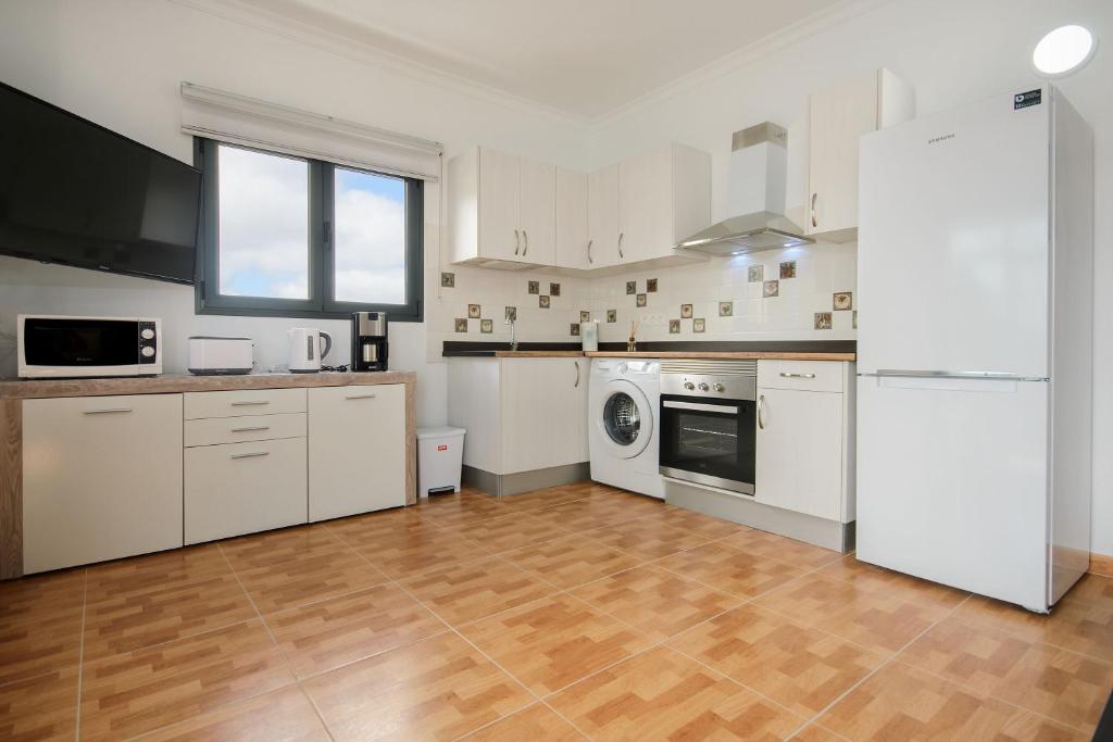 a kitchen with white appliances and a wooden floor at Apartamento Ye in Haría