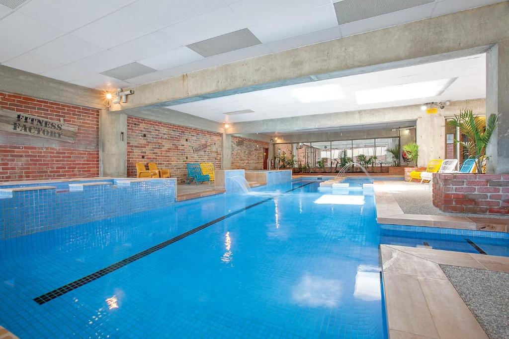 a large swimming pool with blue water in a building at Sovereign Park Motor Inn in Ballarat