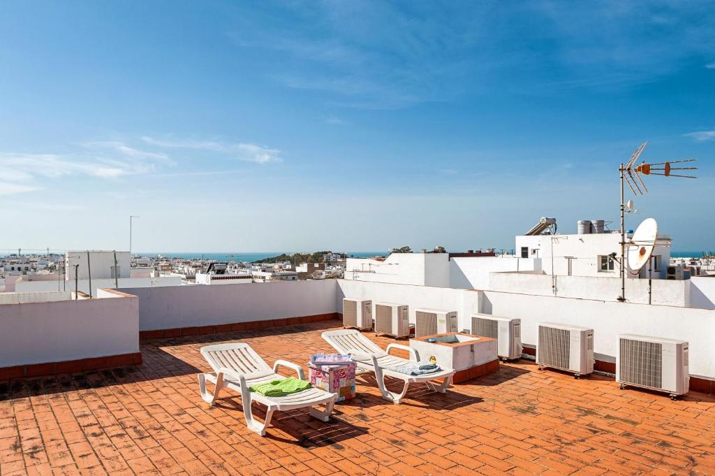 a rooftop with chairs and tables on a roof at Apartamento Frank - solo familias in Conil de la Frontera