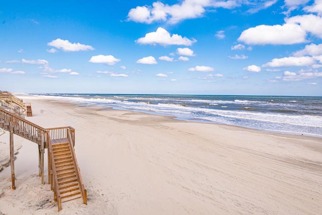 a beach with a wooden staircase leading to the ocean at August Rush in Corolla