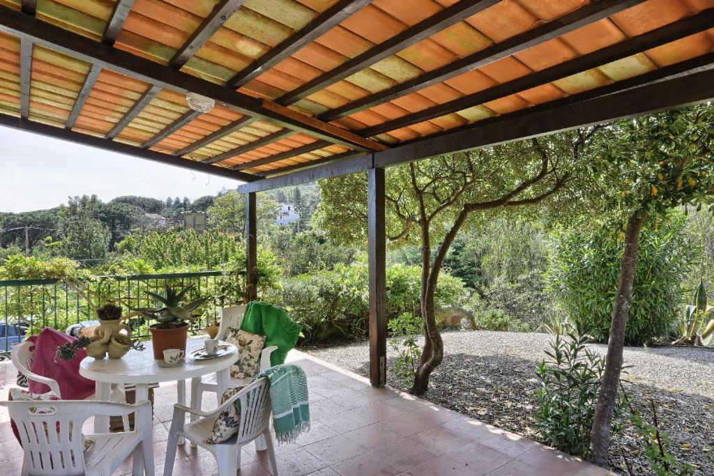 a patio with a table and chairs under a wooden pergola at Il giardino nel sole Trilo in Capoliveri
