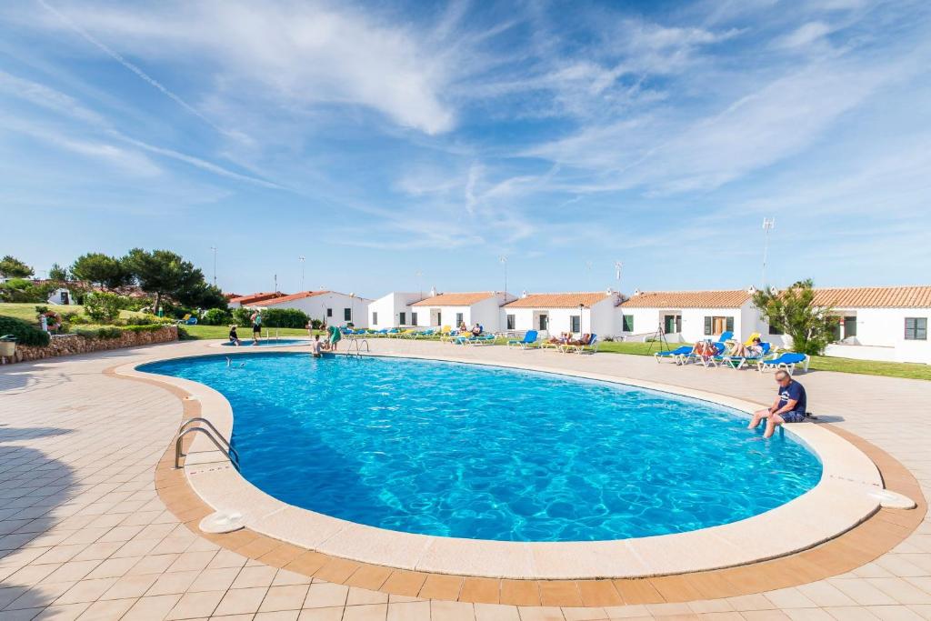 un niño está sentado frente a una piscina en Costa Arenal 45, en Arenal d'en Castell