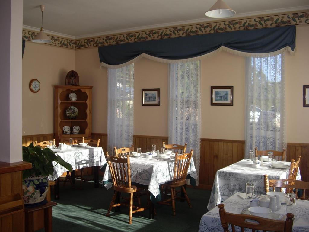 a dining room with two tables and chairs and curtains at Lucinda B&B in Latrobe
