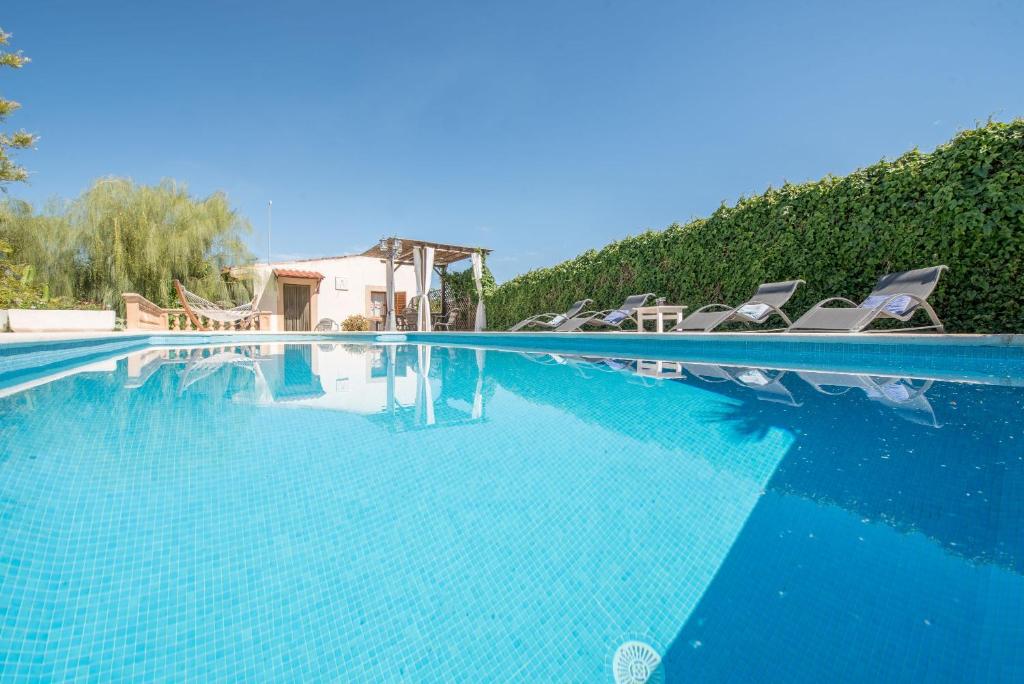 einen Pool mit blauem Wasser und Liegestühlen in der Unterkunft Sa Caseta den Tronca in Sant Joan