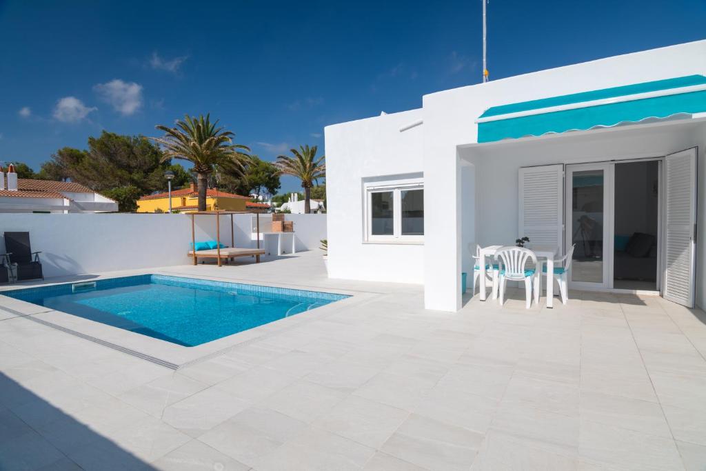 eine weiße Villa mit einem Pool und einer Terrasse in der Unterkunft Villa Izarenar in Cala Blanca