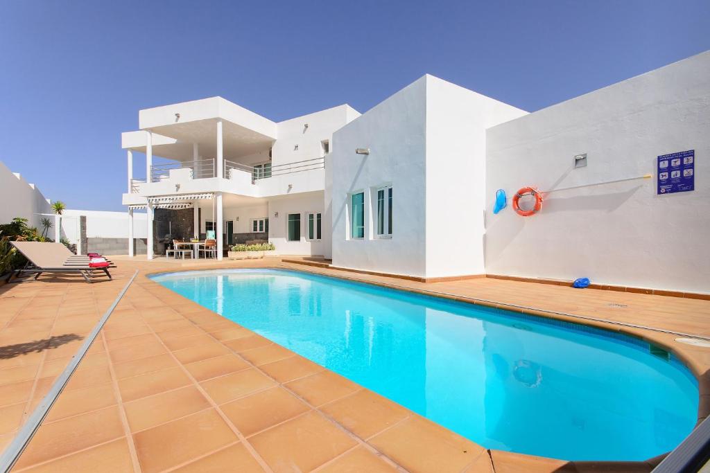 a villa with a swimming pool in front of a house at Las Perseidas in Costa Teguise