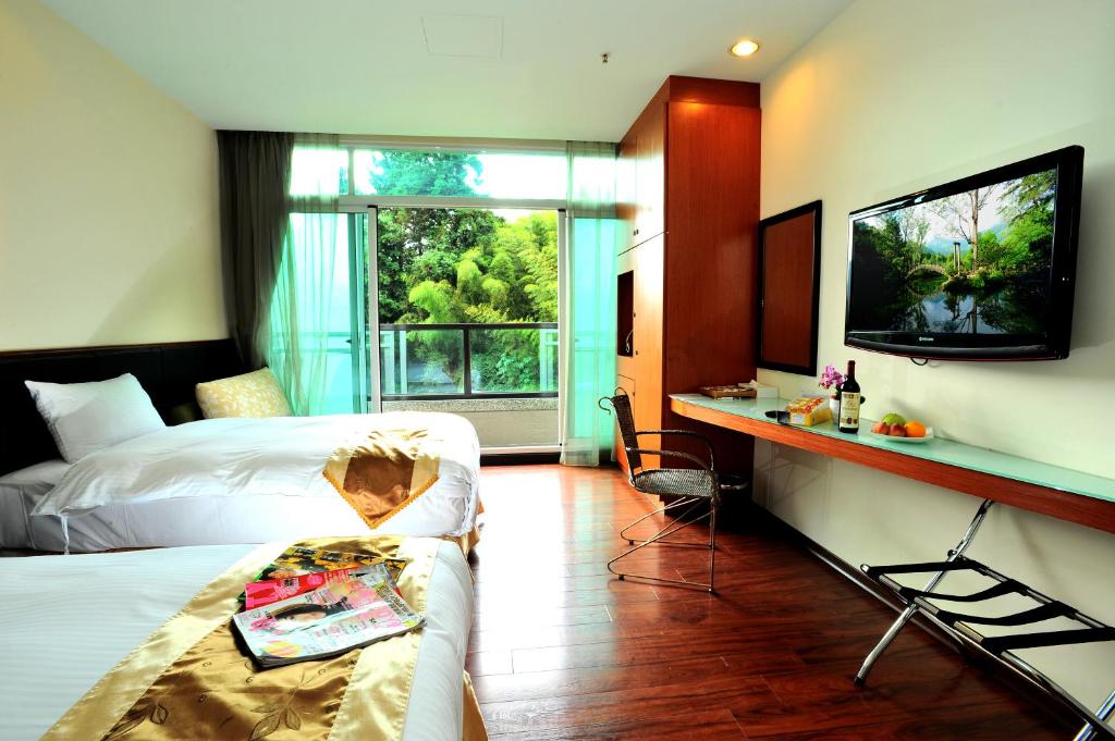 a hotel room with a bed and a desk and a tv at Shante Hotel Shitou in Lugu Lake