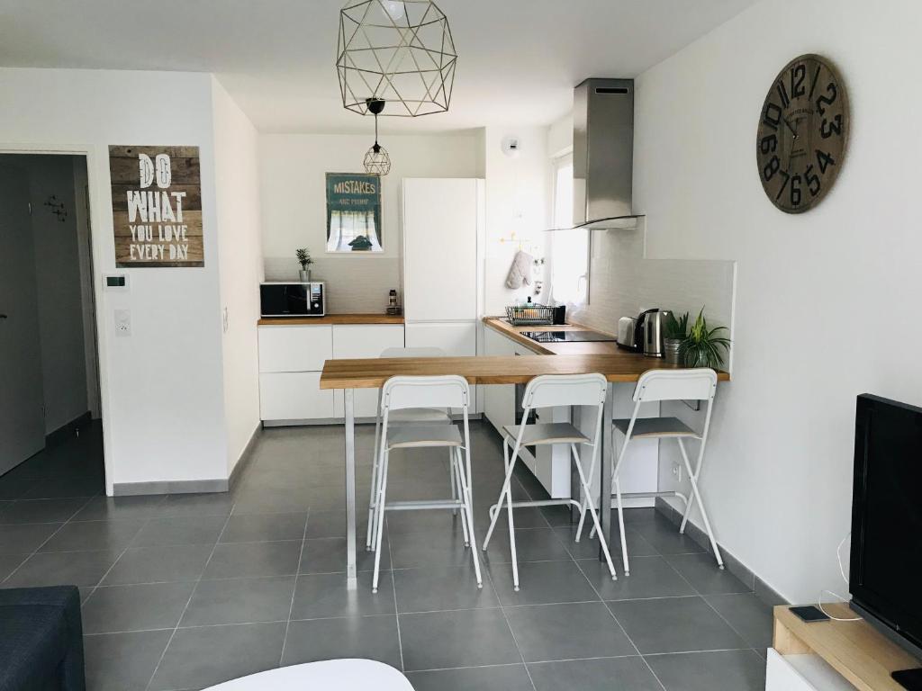 a kitchen with a table and stools in a room at Swann Disney Appartement in Montévrain