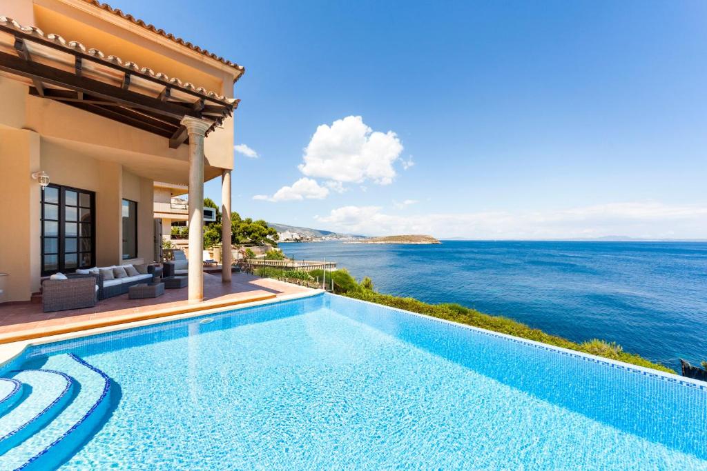 une villa avec une piscine donnant sur l'océan dans l'établissement Villa Juan Carlos, à Cala Vinyes