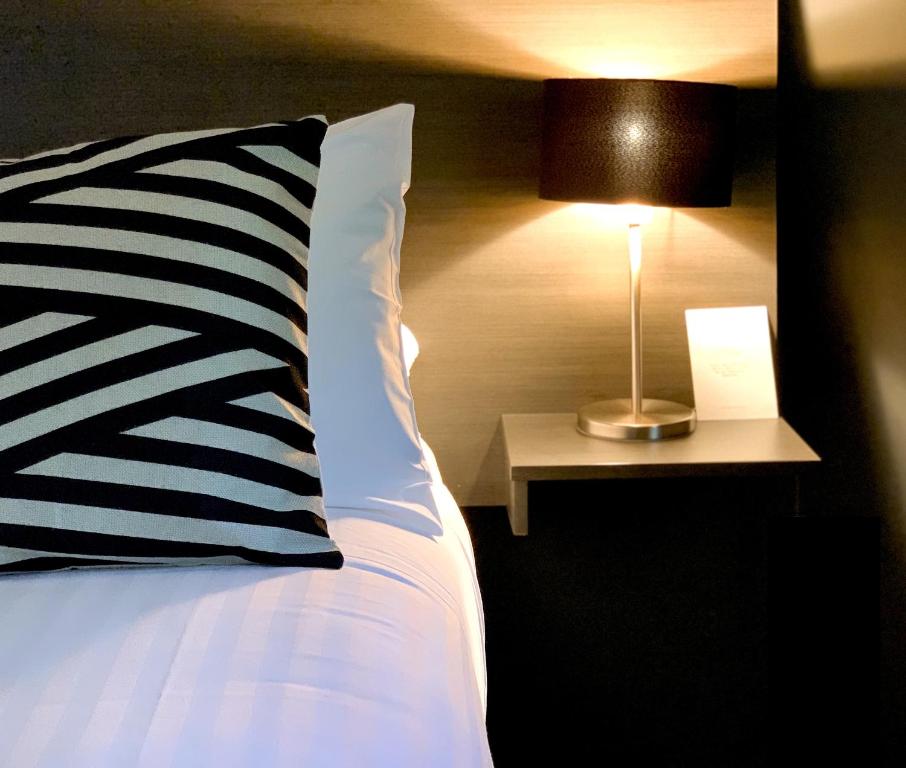 a bed with a black and white pillow and a lamp at Portman House in Scone