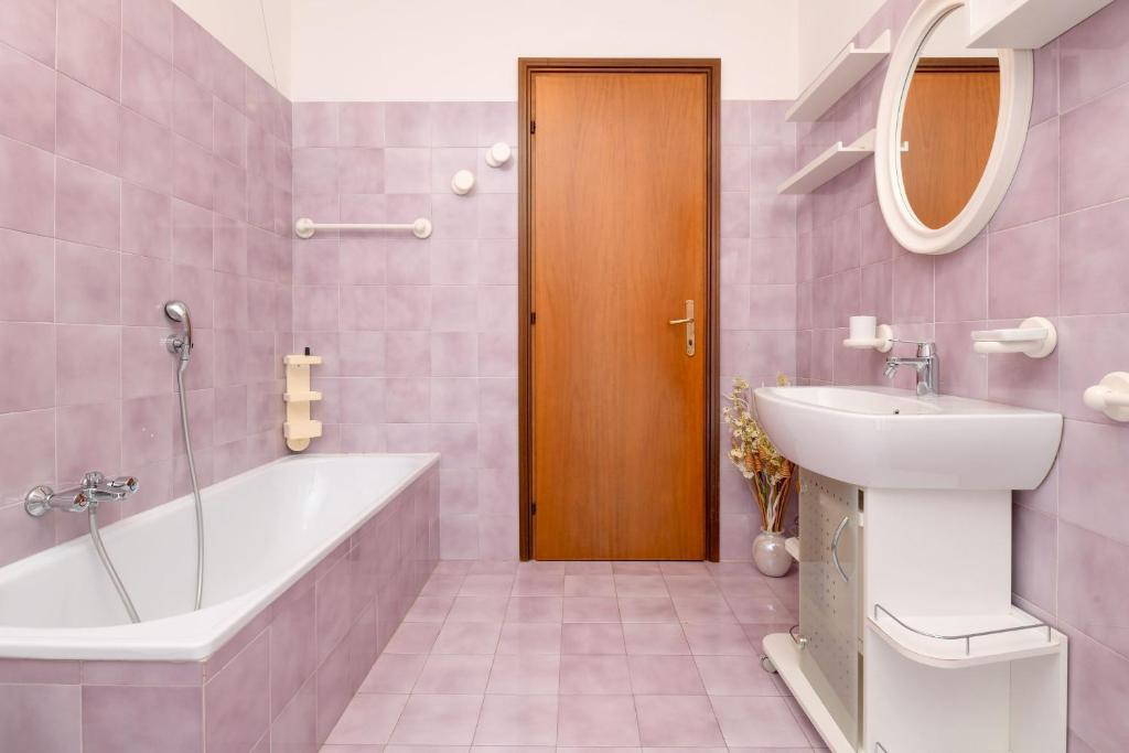 różowa łazienka z wanną i umywalką w obiekcie Civic 55 w mieście Toscolano Maderno